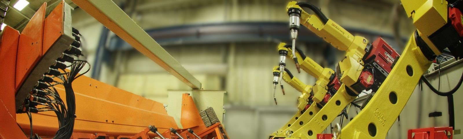 Industrial robotic welding arms positioned inside a guarded automation cell